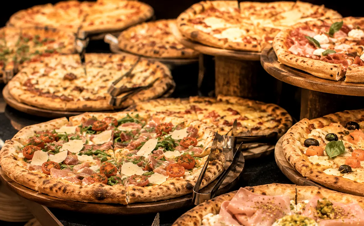 Un buffet de pizzas variées sur des platines en bois, prêtes à être servies.